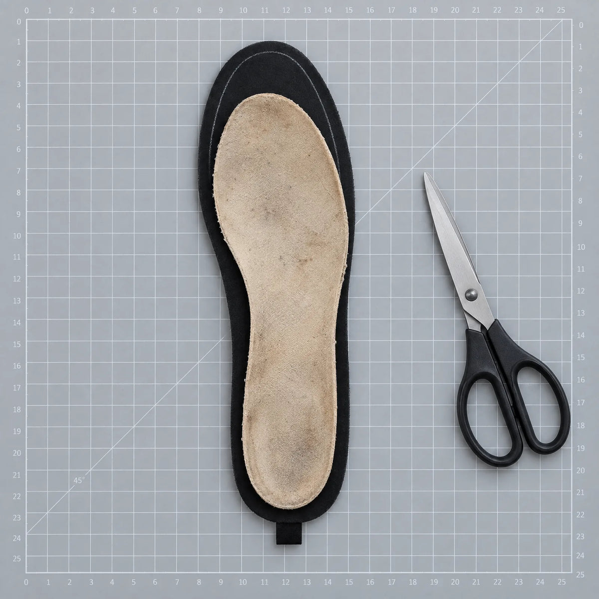 Heated insole with an old insole on top as a template, next to scissors